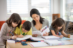Une étudiante d'OpenUni Suisse étudie pendant que ses trois enfants font leurs devoirs