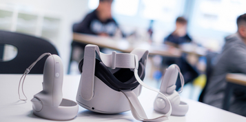 Un casque de réalité virtuel est posé sur une table. On distingue des enfants à l'arrière-plan.