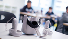 Un casque de réalité virtuel est posé sur une table. On distingue des enfants à l'arrière-plan.